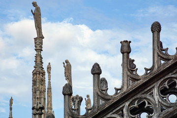 Statue on spire of Milan Cathedral on blue sky background, Milan, Italy. 