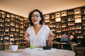 Young laughing woman eating dessert in cafe