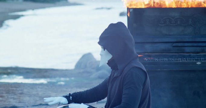 a man in a venetian mask on the sunrise plays the glucophone against the background of a burning old piano