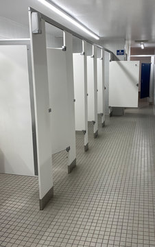 Public restroom with line of bathroom stalls and showers in the back