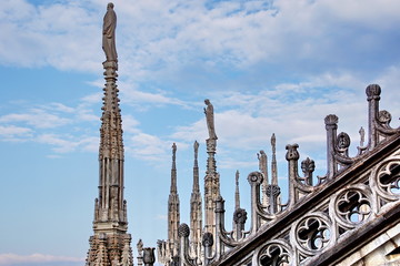 Fototapeta na wymiar Statue on spire of Milan Cathedral on blue sky background, Milan, Italy. 