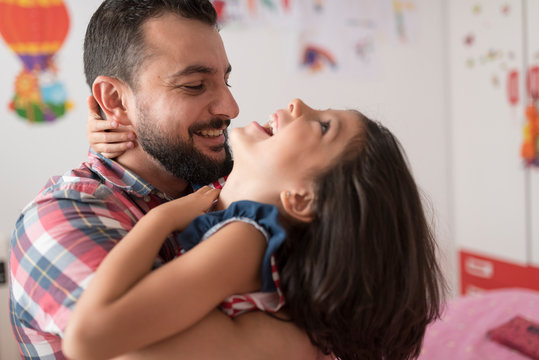 Father hugs and plays with his daughter in the bedroom of their home