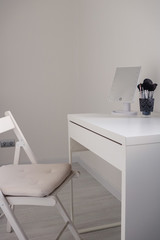 White toilet table dresser with a mirror and a makeup brushes on a white background in a modern interior room