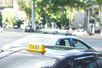 Black taxi cars with yellow standard signs on top parked or stoped on busy city street