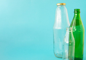 Fototapeta premium Empty glass transparent and green bottles on a blue background. A copy of the space. Ecology and Zero waste concept