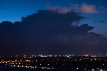 Fototapeta premium Silhouette of a storm cloud in the evening light. Dutch city of The Hague in the foreground.
