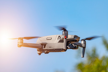 Drone with digital camera flying on the sunny sky. Modern RC quadcopter.