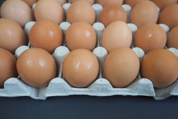 front of a large cardboard container with yellow eggs on a black background side view. lots of raw eggs