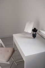 White toilet table dresser with a mirror and a makeup brushes on a white background in a modern interior room