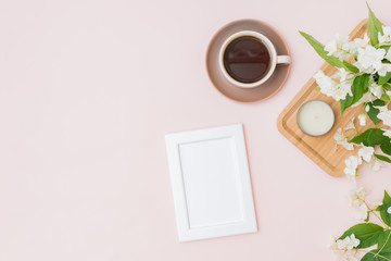 Obraz na płótnie Canvas Mockup white frame with a cup of coffee and jasmine flowers on a color background