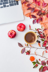 Flat lay composition with colorful autumn leaves, laptop, scarf and a cup of coffee on a white background