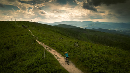 Cycling woman riding on bike in autumn mountains forest landscape. Woman cycling MTB flow trail track. Outdoor sport activity.