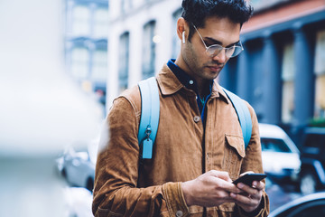 Handsome young Hispanic man texting on smartphone on street
