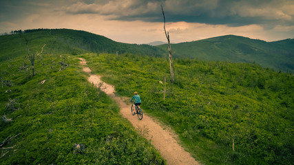 Cycling woman riding on bike in autumn mountains forest landscape. Woman cycling MTB flow trail track. Outdoor sport activity.