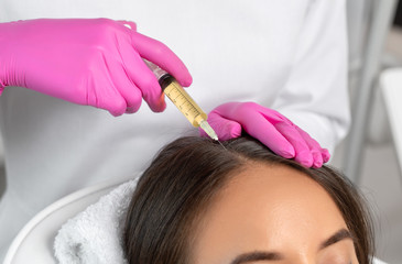Cosmetologist does prp therapy against hair loss and anti-dandruff of a beautiful woman in a beauty salon. Cosmetology concept.