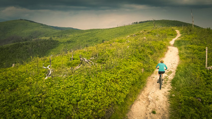 Obraz premium Cycling woman riding on bike in autumn mountains forest landscape. Woman cycling MTB flow trail track. Outdoor sport activity.