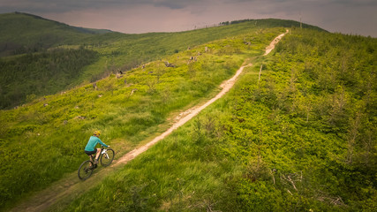 Cycling woman riding on bike in autumn mountains forest landscape. Woman cycling MTB flow trail track. Outdoor sport activity.