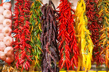 Naklejka premium A variety of chillies hanging on display at La Boqueria market in Barcelona, Spain. 