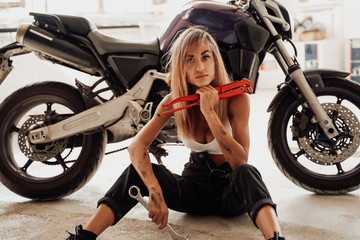 Fototapeta na wymiar A bright garage and sitting girl with sport bike inside