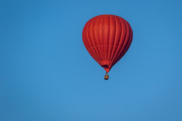 Bright red hot air balloon in flight against a background of blue sky. Colorful watercolor painting balloon flying high. Close-up.