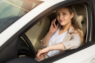 beautiful young woman driving a car with a phone in hand