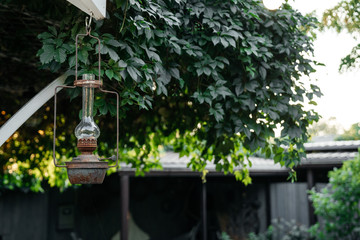 Vintage vintage lantern hangs on the porch of a private house on a background of greenery in the evening.