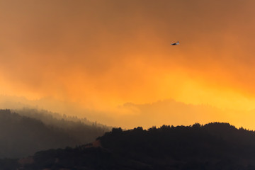 Heroes Fly Here - Fire aircraft returns to Sonoma County (CA) Airport against smoke backlit by the setting sun. Santa Rosa, California, USA