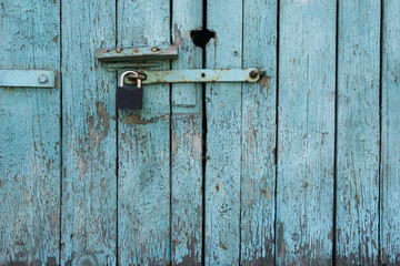 Old wooden door with blue painted planks closed with a padlock. Grunge background.