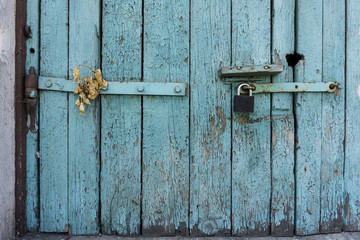 Old wooden door with blue painted planks closed with a padlock. Grunge background.