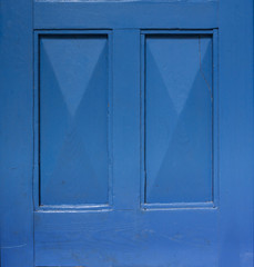 Detail of an old wooden blue painted door. Blue background. Blue rectangular frame.
