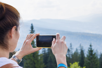 Woman tourist photographs the mountainous area .