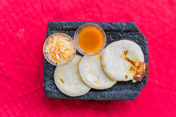 top view of a typical Salvadoran dish, rice and corn pupusas, pickles and tomato sauce