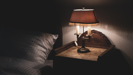 Bedside nightstand table with antique retro vintage lamp low key photography relaxing bedtime - obrazy, fototapety, plakaty