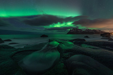 Northern lights (Aurora Borealis) over the starry night sky. Uttakleiv beach in Lofoten, Norway