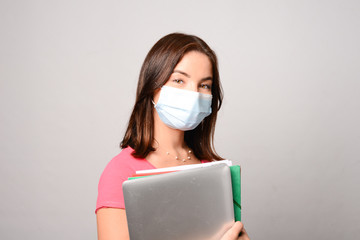 portrait of beautiful young girl student isolated on white background wearing a covid 19 surgical mask protection