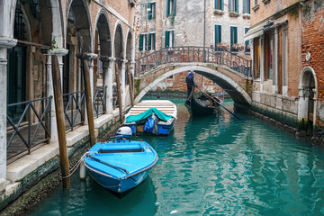 Fototapeta na wymiar Gondolier riding a gondola under the beautiful Ponte del Piovan bridge in a Venetian water canal. At Venice, Italy