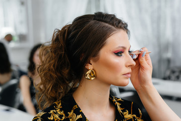 In a beautiful, modern beauty salon, a professional makeup stylist makes makeup for a young girl....