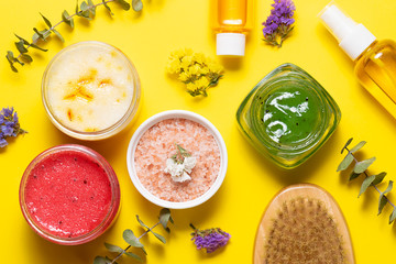 Natural homemade cosmetic, Himalaya salt, essential oils and brush for dry massage on bright yellow background top view. Home spa concept.