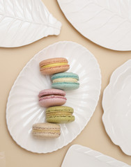 Macarons in white plate on beige background.