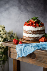 Naked cake with cream, decorated with strawberry and mint. Chocolate cake.