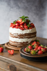 Naked cake with cream, decorated with strawberry and mint. Chocolate cake.