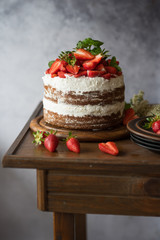 Naked cake with cream, decorated with strawberry and mint. Chocolate cake.