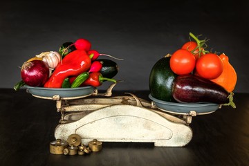 Fresh vegetables and old kitchen scale on a black background. Harvest of vegetables. Healthy food.