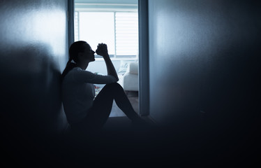 silhouette of a woman indoors next to window praying