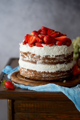 Naked cake with cream, decorated with strawberry and mint. Chocolate cake.