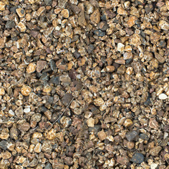 Small stones of seamless texture. Seamless surface texture covered with small dark brown stones.