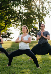 A group of people do yoga in the Park at sunset. Healthy lifestyle, meditation and Wellness