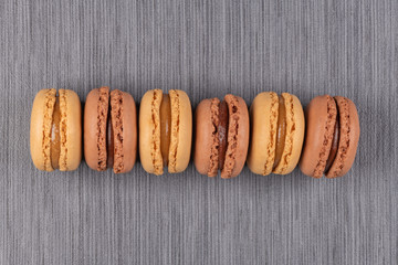 Six coffee and chocolated flavoured macaroons on vinyl background