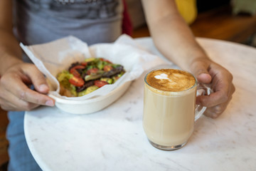 man holding coffee eating avocado toast