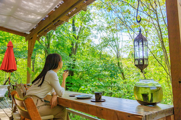 自然のカフェでコーヒーを楽しむ女性の後ろ姿